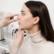 A doctor examining a woman’s nose during a rhinoplasty consultation