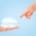 Female hand pointing at breast implants against a blue background, illustrating breast augmentation proportion.