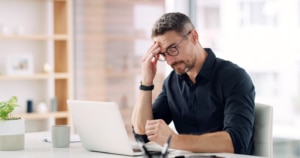 Man experiencing fatigue and trouble focusing at work due to low testosterone.