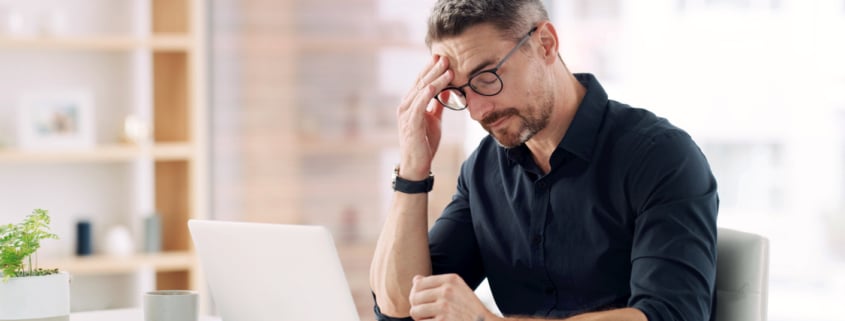 Man experiencing fatigue and trouble focusing at work due to low testosterone.